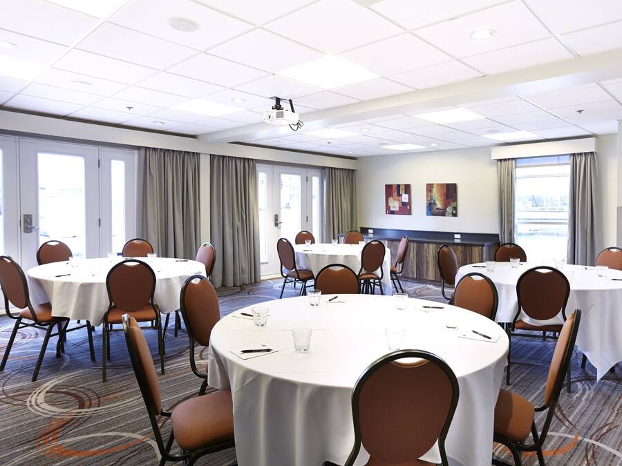 A conference room with round tables, chairs, and a projector.
