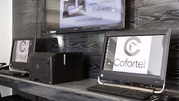 Un mostrador de recepción de hotel con un monitor que muestra el nombre y sitio web del hotel, una impresora y un teclado.