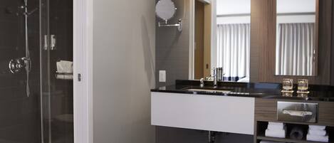 A modern bathroom with a glass-enclosed shower, a large bathtub, and a vanity with a mirror and countertop.