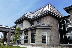 Een modern gebouw met een gevel van natuursteen, grote ramen en een metalen dak.