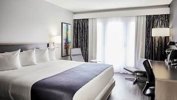 Ein Hotelzimmer mit einem großen Bett, einem Schreibtisch, einem Stuhl und einem kleinen Tisch.