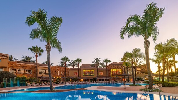 A resort pool with palm trees and a building with multiple balconies. - Elba Costa Ballena Beach & Thalasso Resort (Rota)