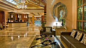 A spacious lobby with a reception desk, a large mirror, and a seating area with a sofa and armchairs. - Elba Costa Ballena Beach & Thalasso Resort (Rota)