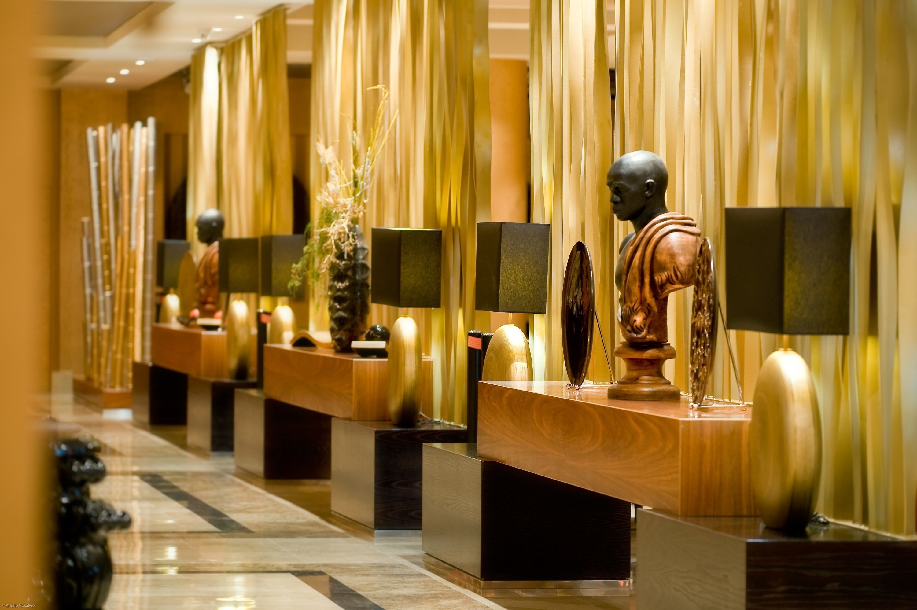 A hotel reception area with a series of wooden reception desks, each with a black panel and a decorative item on top.