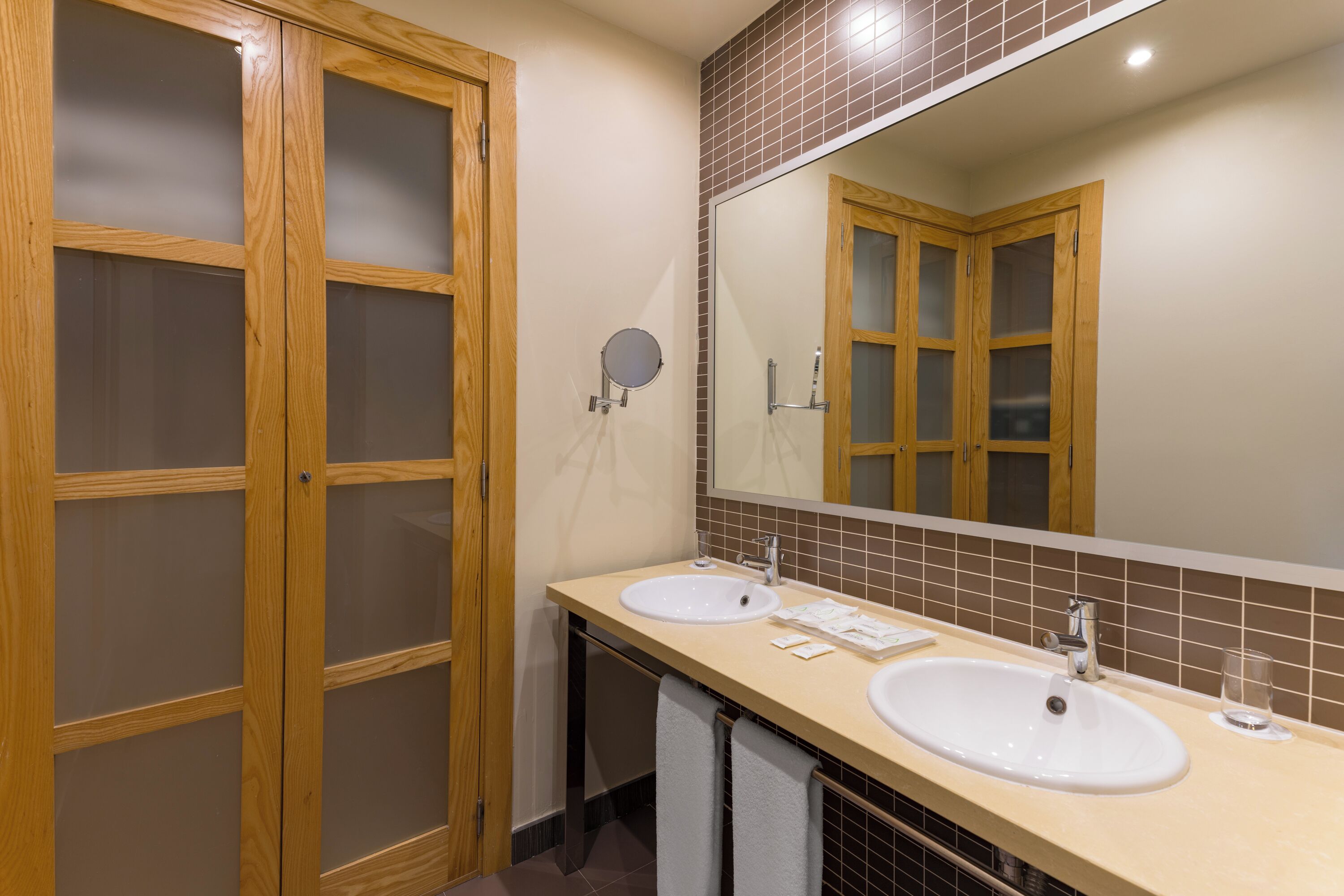 A bathroom with two sinks, a mirror, and wooden cabinets.
