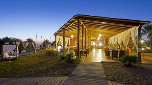 A covered outdoor dining area with tables and chairs, a wooden deck, and a pathway leading to the entrance. - Elba Costa Ballena Beach & Thalasso Resort (Rota)