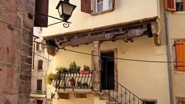 Ein Gebäude mit einer Treppe, die zu einem Balkon führt, einer Straßenlaterne und einer Tür mit grünem Rahmen.