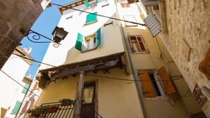 Eine enge Straße mit Gebäuden im traditionellen Baustil, darunter Balkone mit Holzgeländern und Fensterläden.