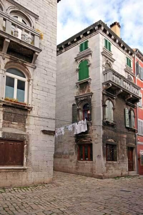 Un edificio histórico de piedra con ventanas de arco y un balcón.