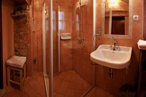 Een badkamer met een glazen douchecabine, een wastafel en een spiegel.