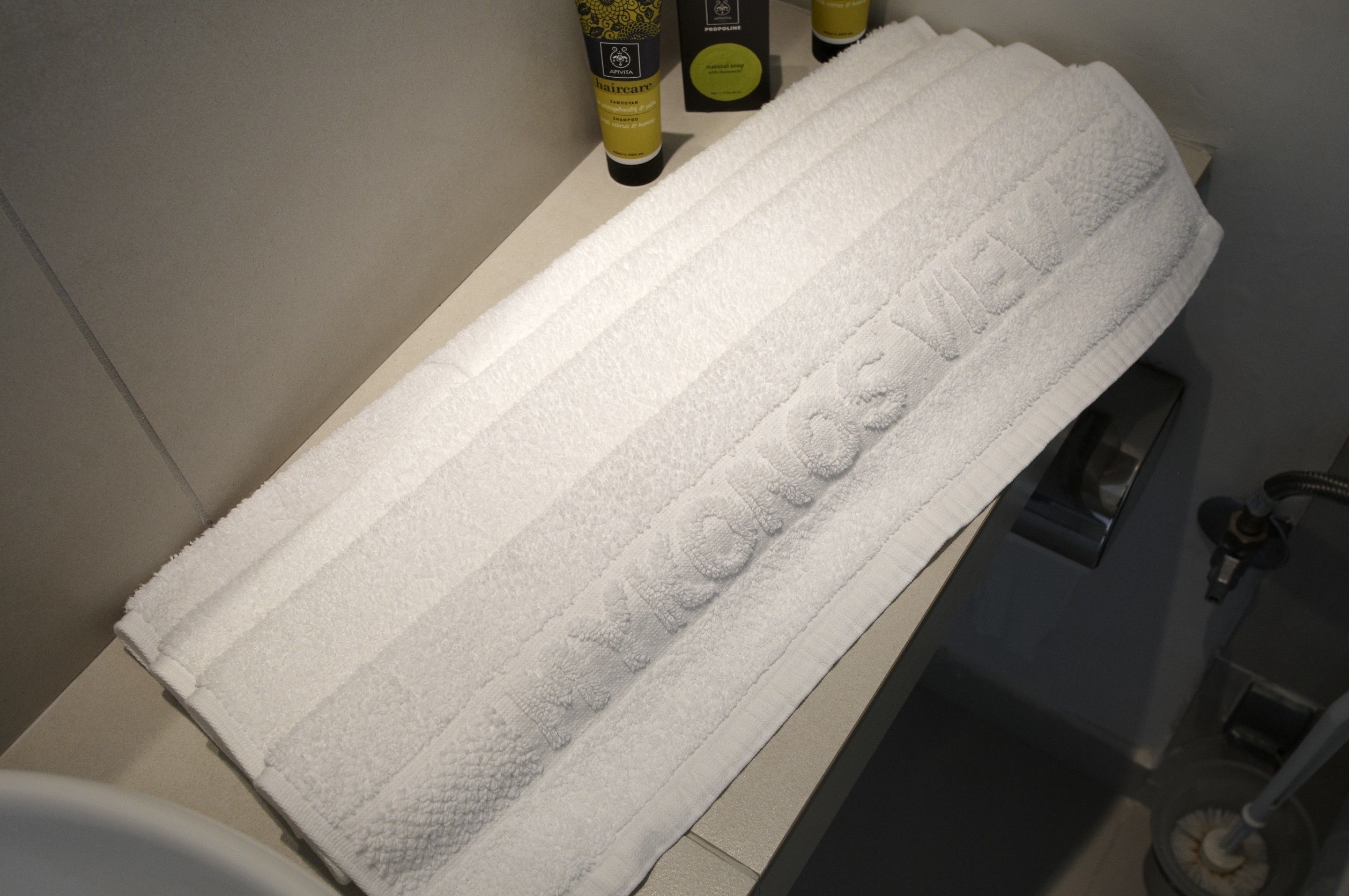 Ein weißes Handtuch mit geprägtem Text auf einer Badezimmerablage.