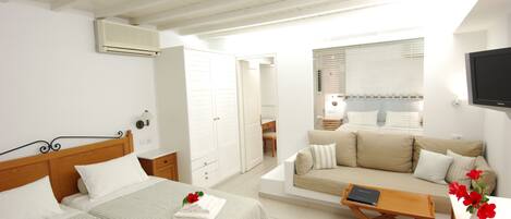 Habitación de hotel con dos camas, un sofá, un televisor y una ventana con persianas.
