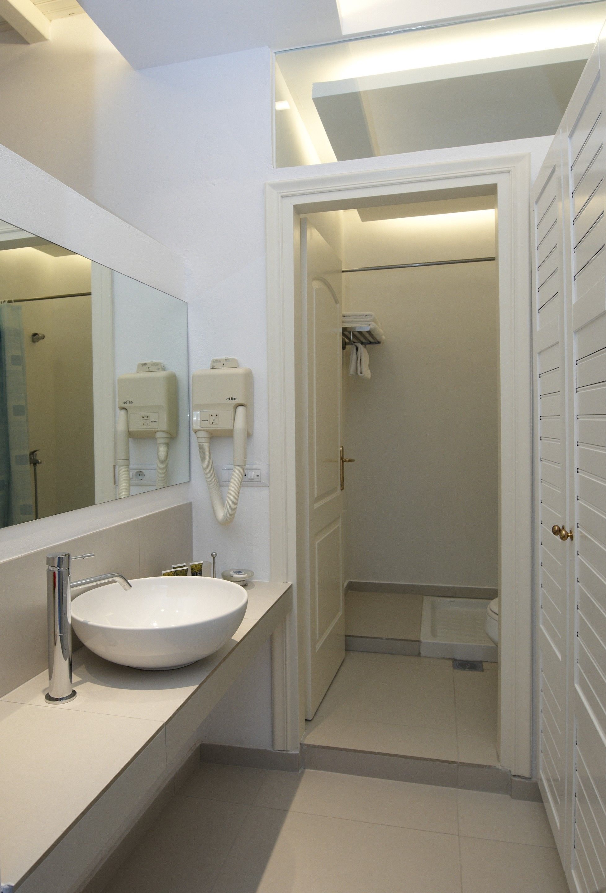 A modern bathroom with a large mirror, a white sink, and a shower area.
