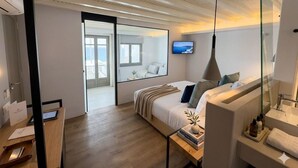 A modern hotel room with a bed, bedside table, TV, and a large window. - Mykonos View (Mykonos)