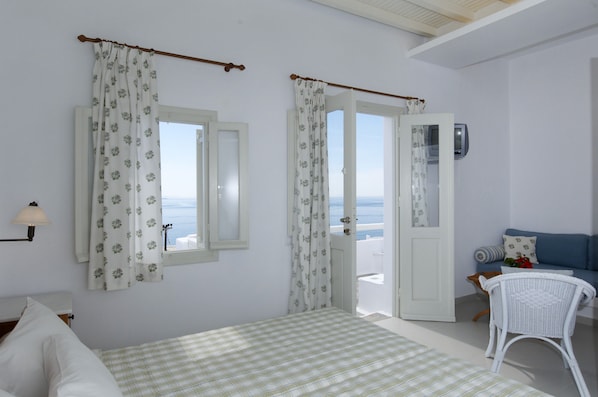 A bedroom with a bed, a chair, a TV, and a view of the sea. - Mykonos View (Mykonos)