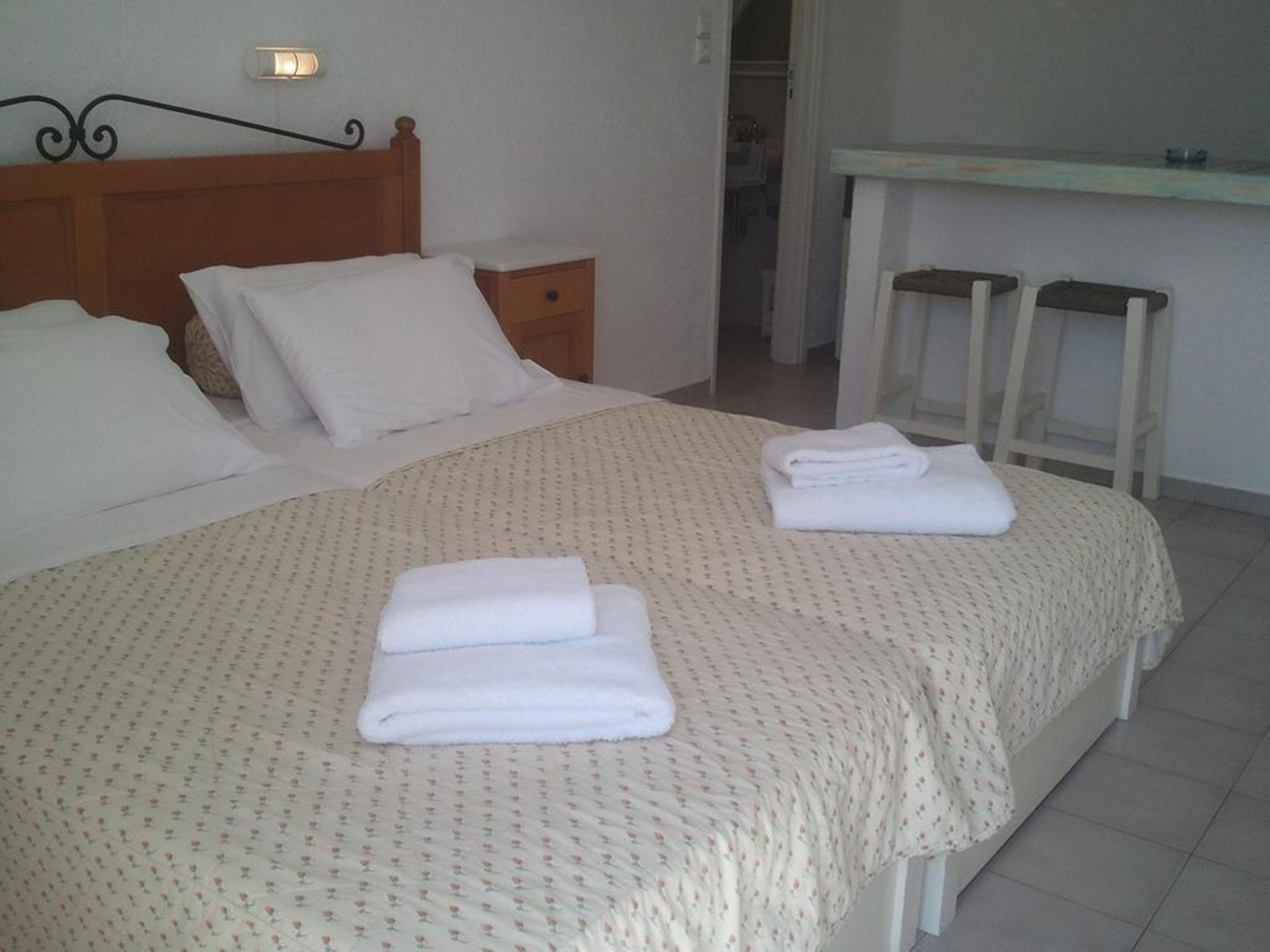 A neatly made bed with a floral-patterned bedspread and two folded towels.