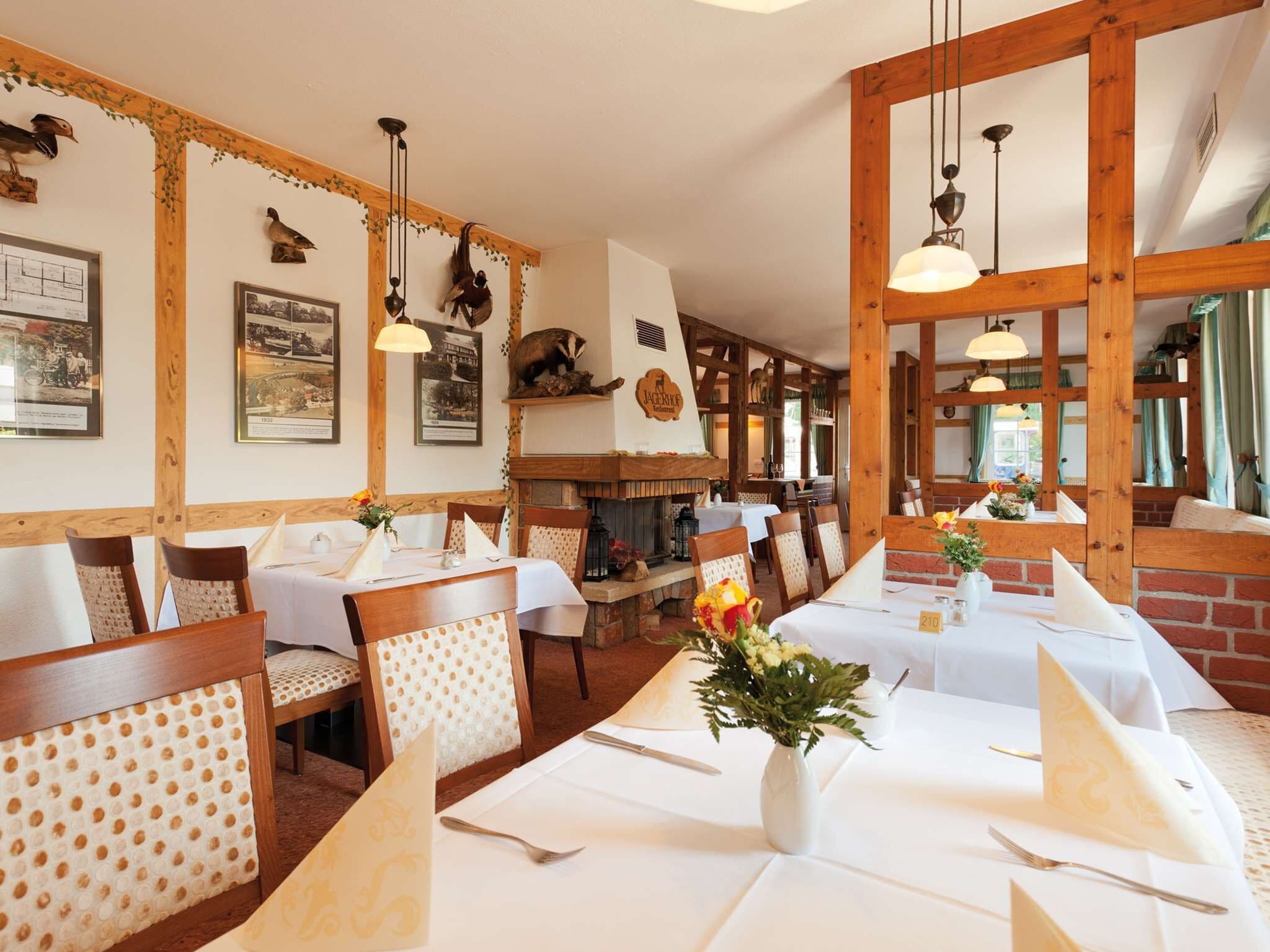 Een restaurant met houten balken, witte tafellinnen en bloemstukken.