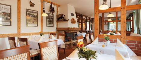 A restaurant with wooden beams, white tablecloths, and floral centerpieces.