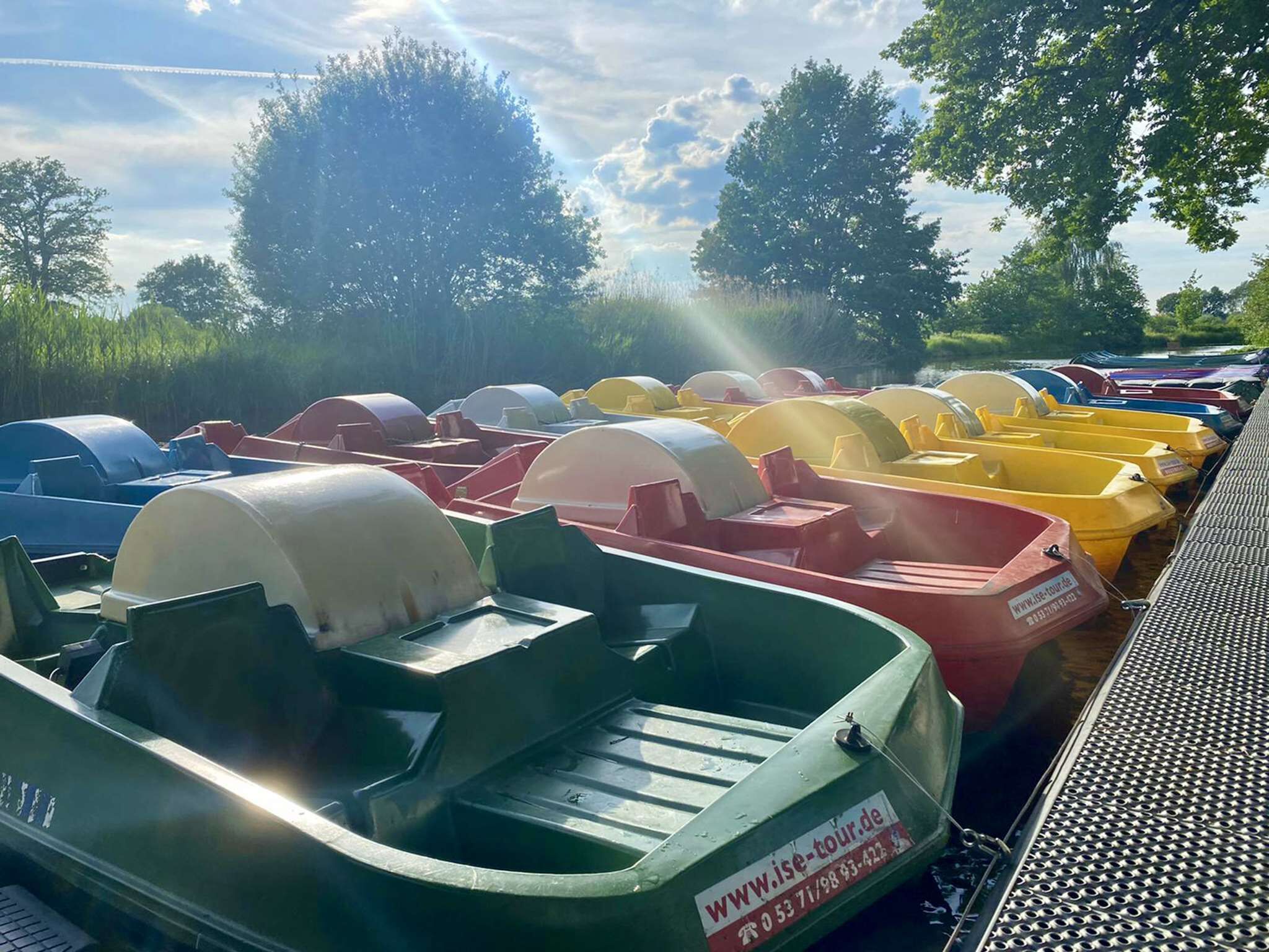A row of colorful pedal boats parked by a body of water.