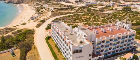 A coastal hotel with multiple floors, a beachside location, and a view of the ocean.