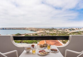Ein Tisch mit Speisen und Getränken mit Blick auf eine Küstenlandschaft mit Klippen und einem Strand.