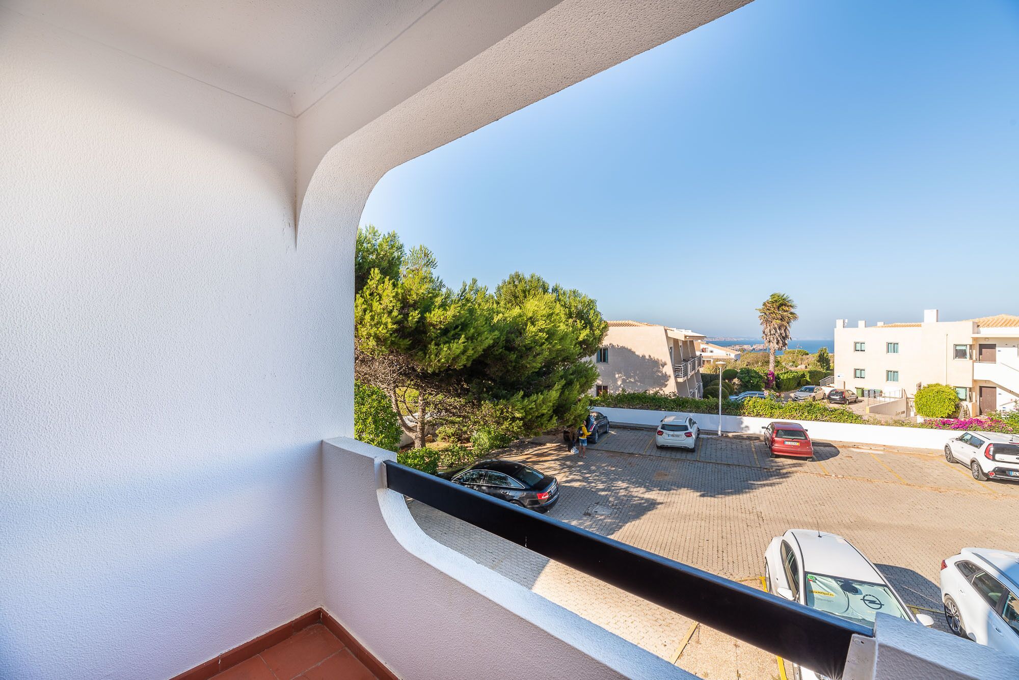 A balcony with a clear view of a parking area and buildings in the background.