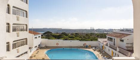 Una piscina en la azotea con vistas despejadas del paisaje circundante, incluyendo colinas lejanas y edificios.