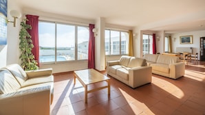A spacious living room with large windows, a sofa, a coffee table, and a view of the sea. - Aparthotel Navigator (Vila do Bispo)