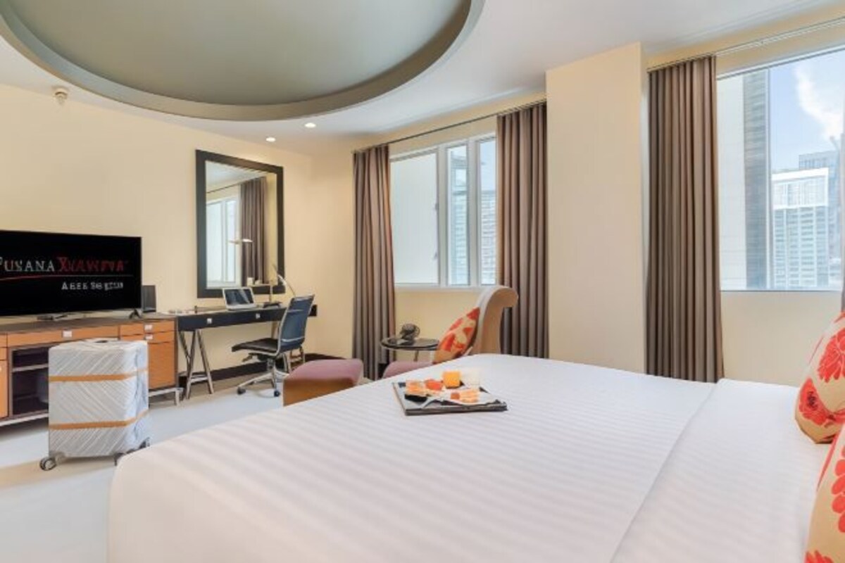 A hotel room with a bed, a desk, a television, and a window with curtains.