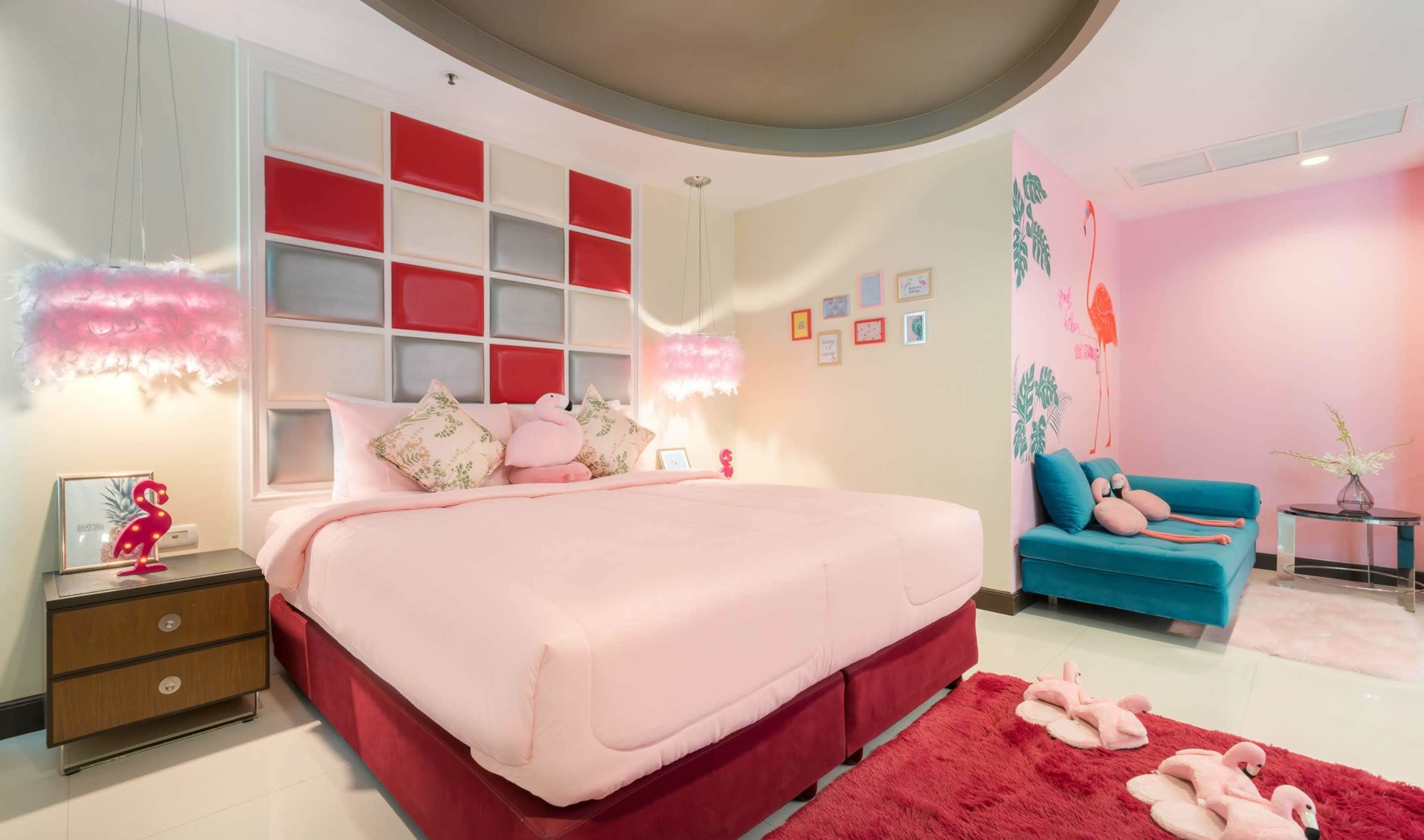 Une chambre avec un grand lit, un canapé bleu et un tapis rouge.