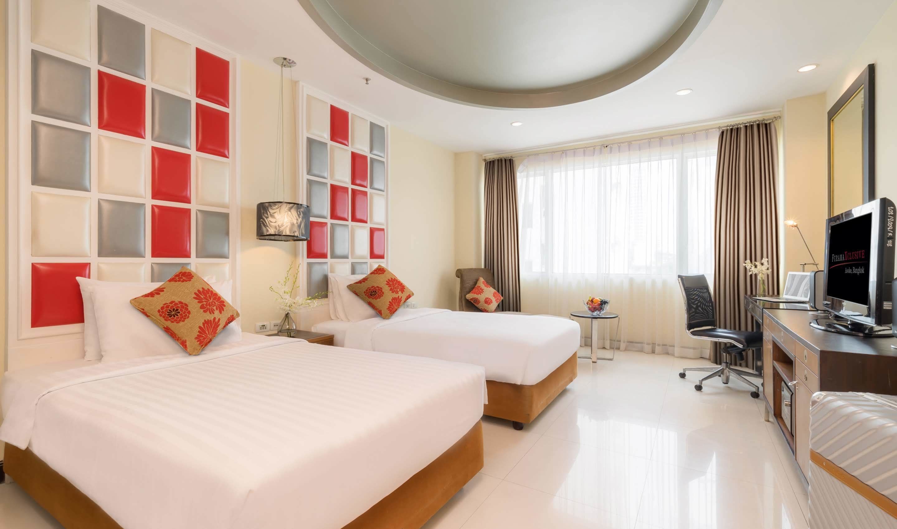 A hotel room with two beds, a desk with a computer, a chair, and a TV.