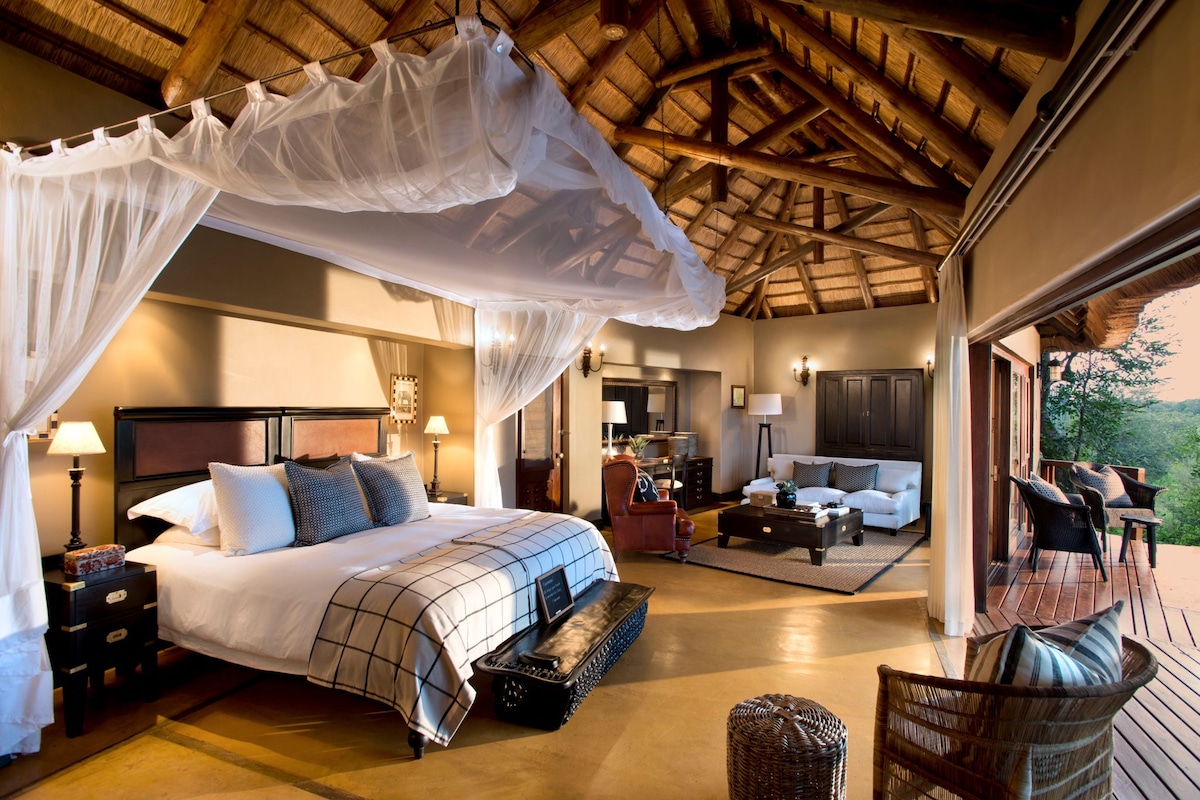 Une chambre spacieuse avec un grand lit, un baldaquin et une vue sur l’extérieur.