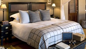A bed with a canopy, bedside tables, a nightstand, a chair, and a tray with books and decorative items.