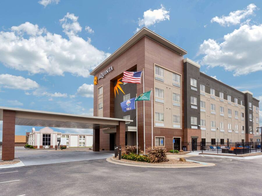 A hotel with a modern design, featuring a prominent entrance, a covered parking area, and multiple flags.