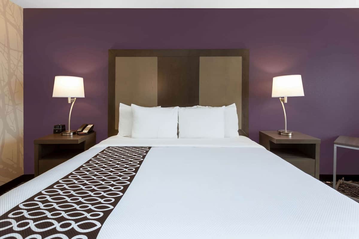 A hotel room with a large bed, two bedside tables with lamps, and a patterned runner.