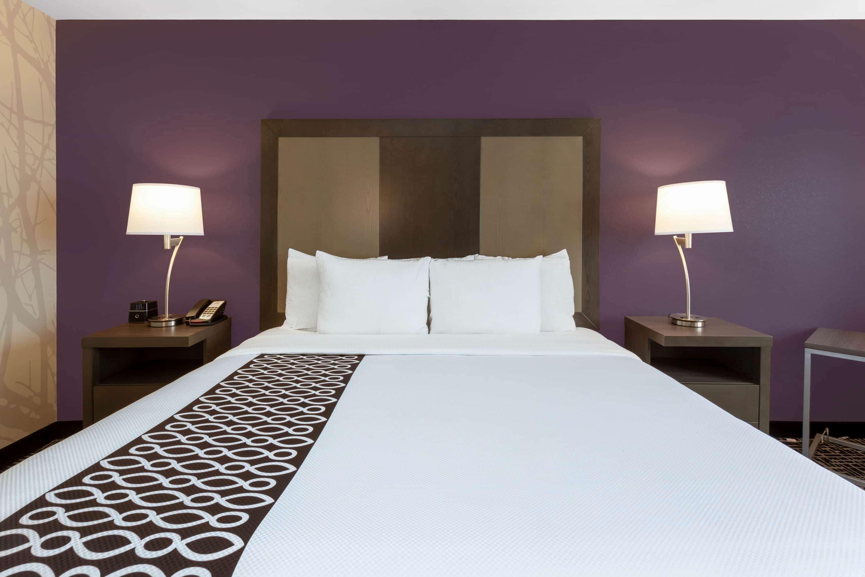A hotel room with a large bed, two bedside tables with lamps, and a patterned runner.