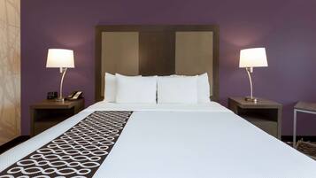 A hotel room with a large bed, two bedside tables with lamps, and a patterned runner.