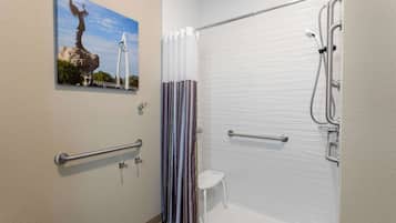 A bathroom with a shower, a handrail, a small white stool, and a painting of a bridge and statue.