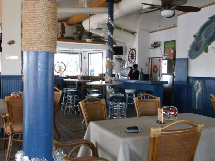 A restaurant interior with wooden chairs, tables, and a bar area.