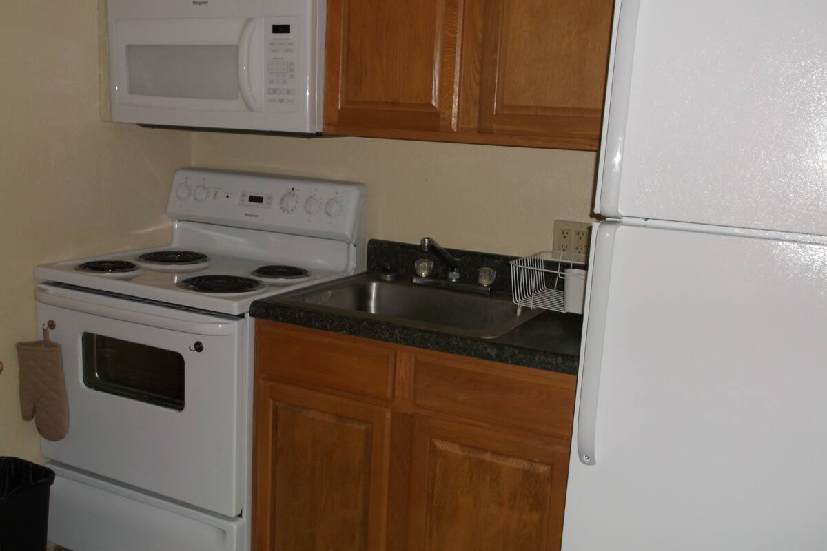A kitchen with a stove, oven, microwave, and sink.