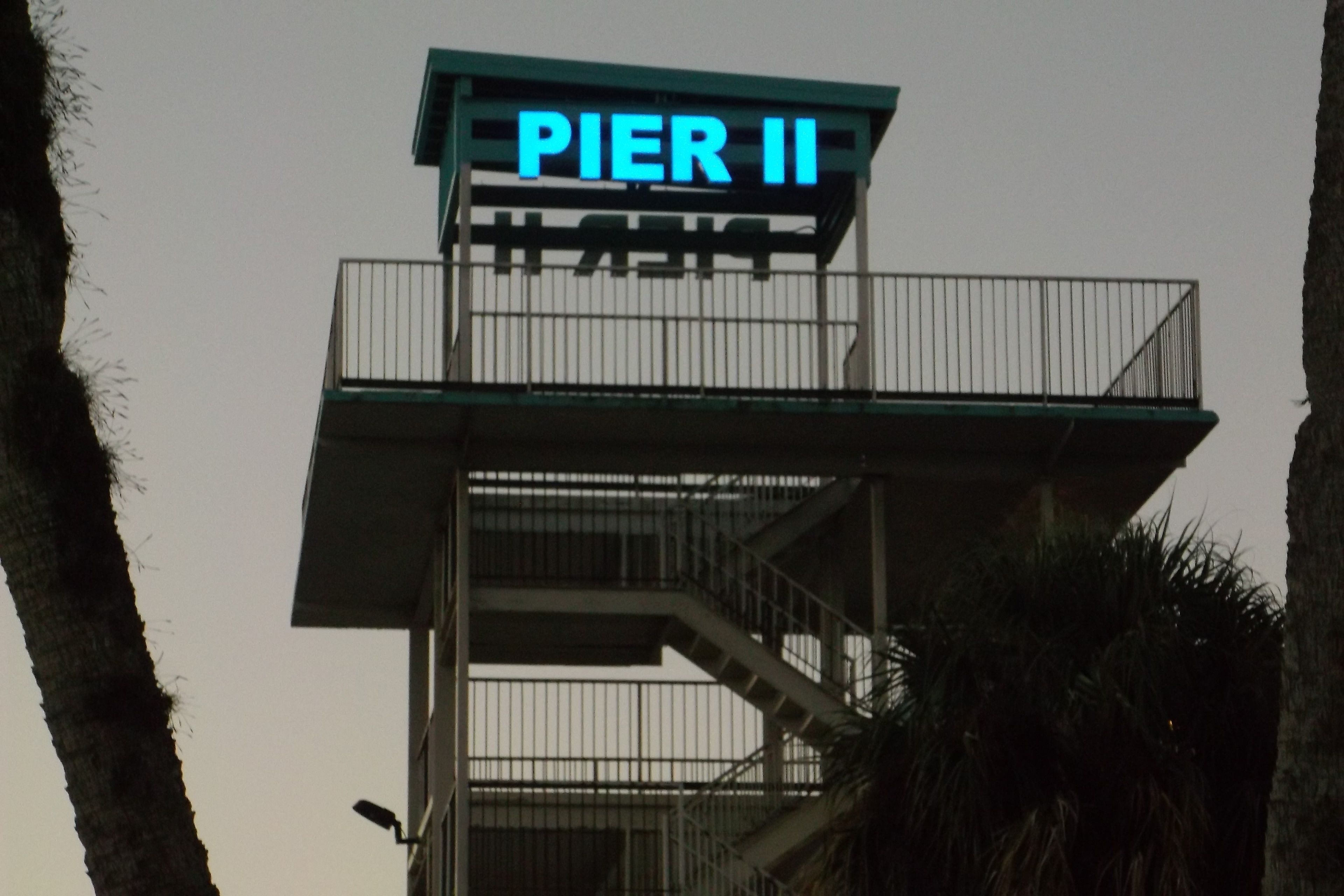 A sign reading "PIER II" on a structure with a balcony and stairs.