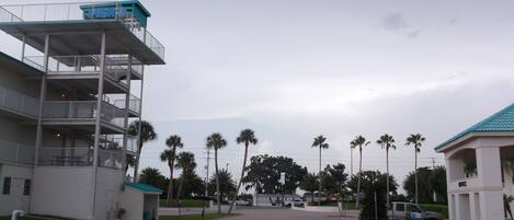 A multi-story hotel with a parking area and palm trees.