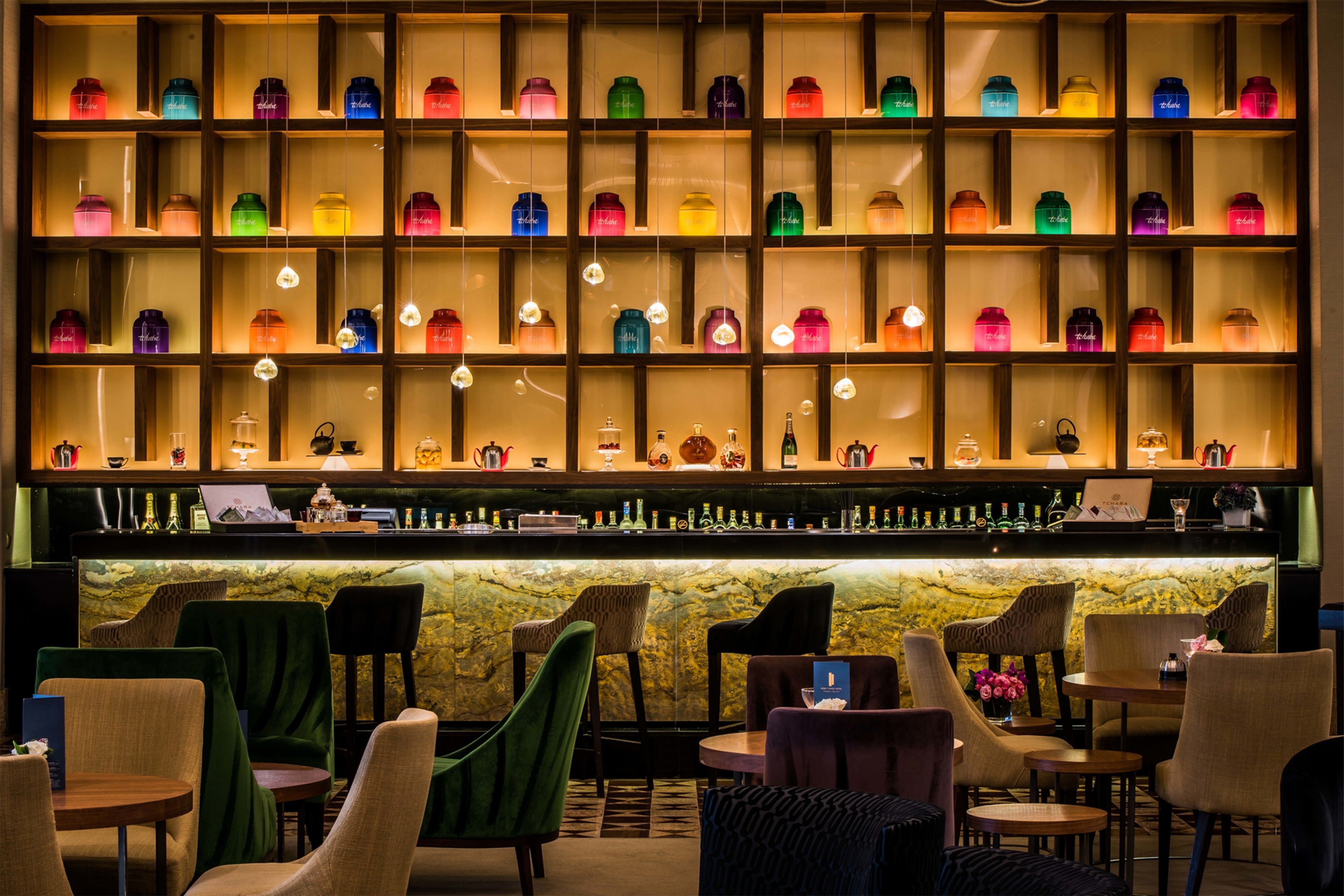 A bar area with shelves of colorful bottles, a marble counter, and various seating arrangements.