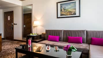 A modern hotel room with a sofa, a coffee table with decorative items, a lamp, and a framed painting on the wall.