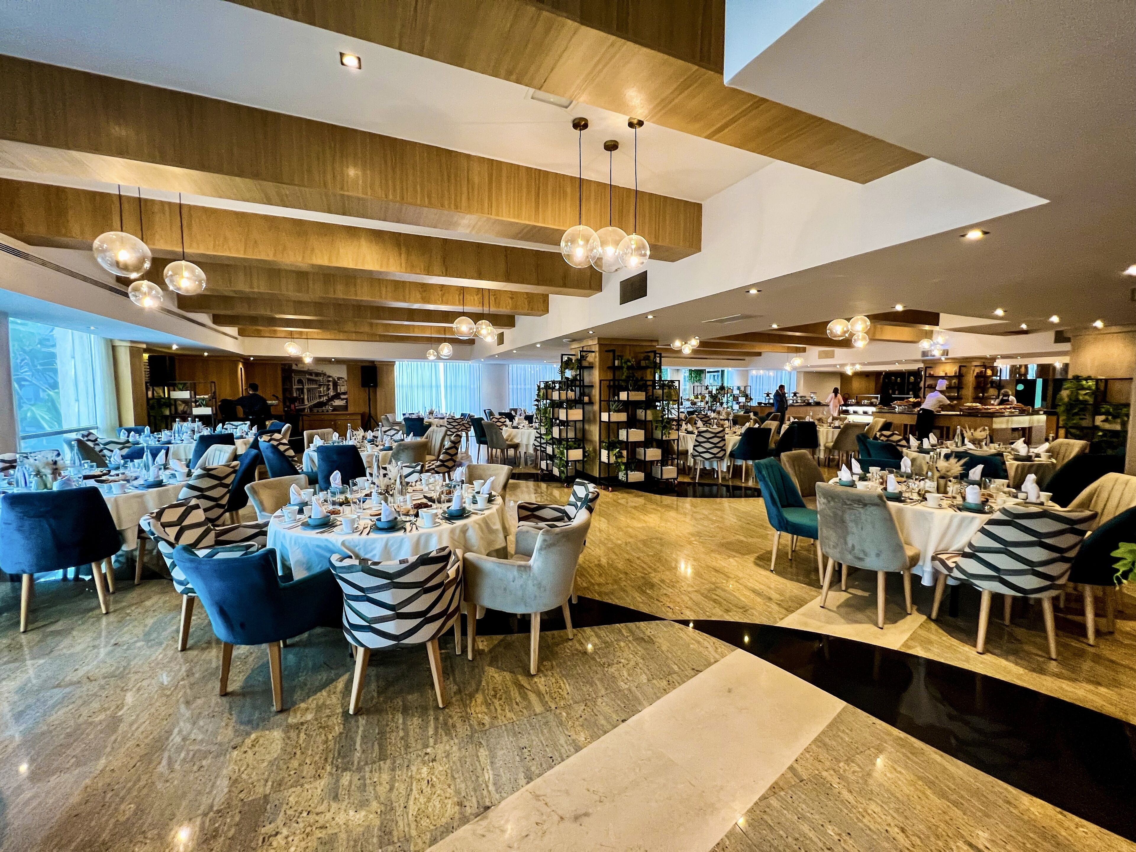 Een ruim restaurant met meerdere tafels en stoelen, een bar en een modern interieur.