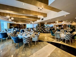 Un restaurante espacioso con numerosas mesas y sillas, una zona de bar y un diseño interior moderno.