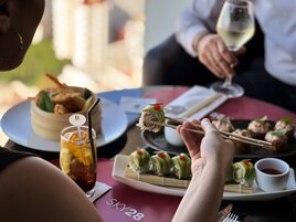 Una mesa con sushi, un vaso de té helado y una copa de vino.