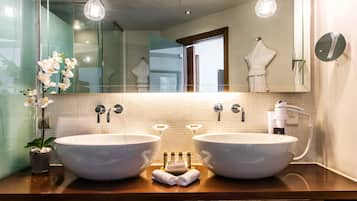 Une salle de bain avec deux grands lavabos, un porte-serviettes, un miroir et une orchidée en pot.