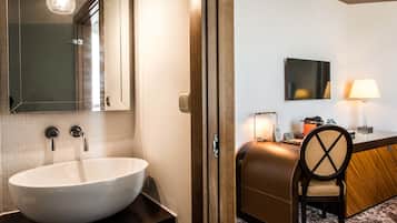 Un baño moderno con un lavamanos grande de color blanco, un espejo y un mueble de tocador de madera.