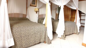 Una habitación con dos camas, cada una con dosel y mesita de noche con lámpara.